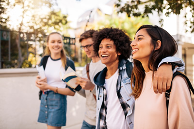 Group of teenage students with backpacks and books walking