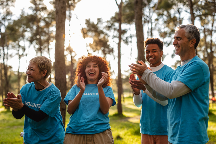 Group of volunteers in blue t-shirts clapping and laughing together